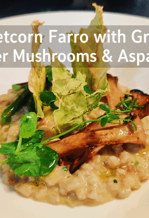 Sweetcorn Farro topped with grilled oyster mushrooms, asparagus, and pea shoots served on a white plate.